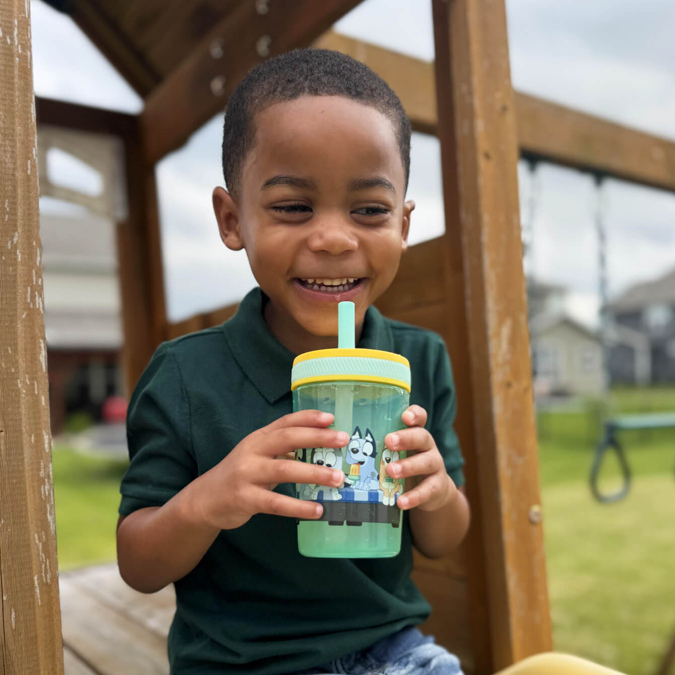Child at playground holding a bluey straw water cup