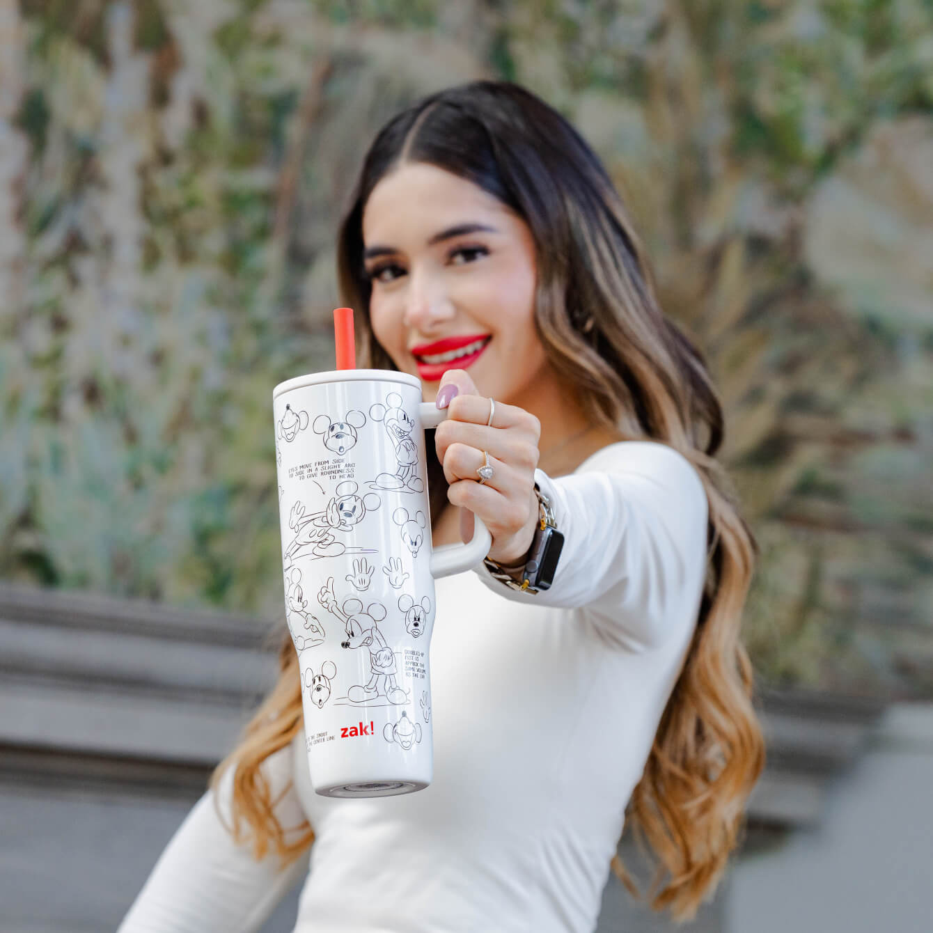 woman with dark hair holding a white and red tumbler by the handle