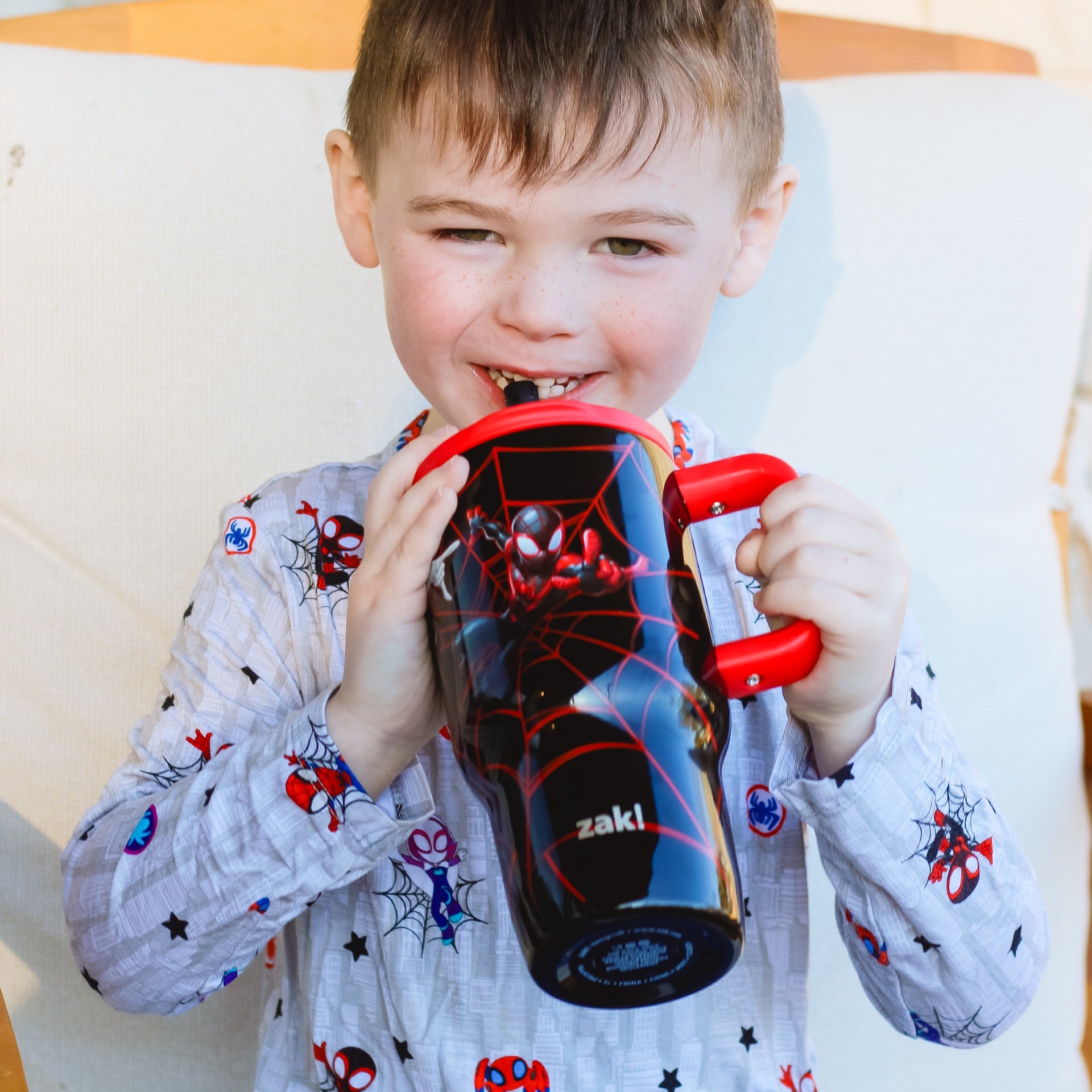 Boy sipping from Spiderman tumbler with red handle