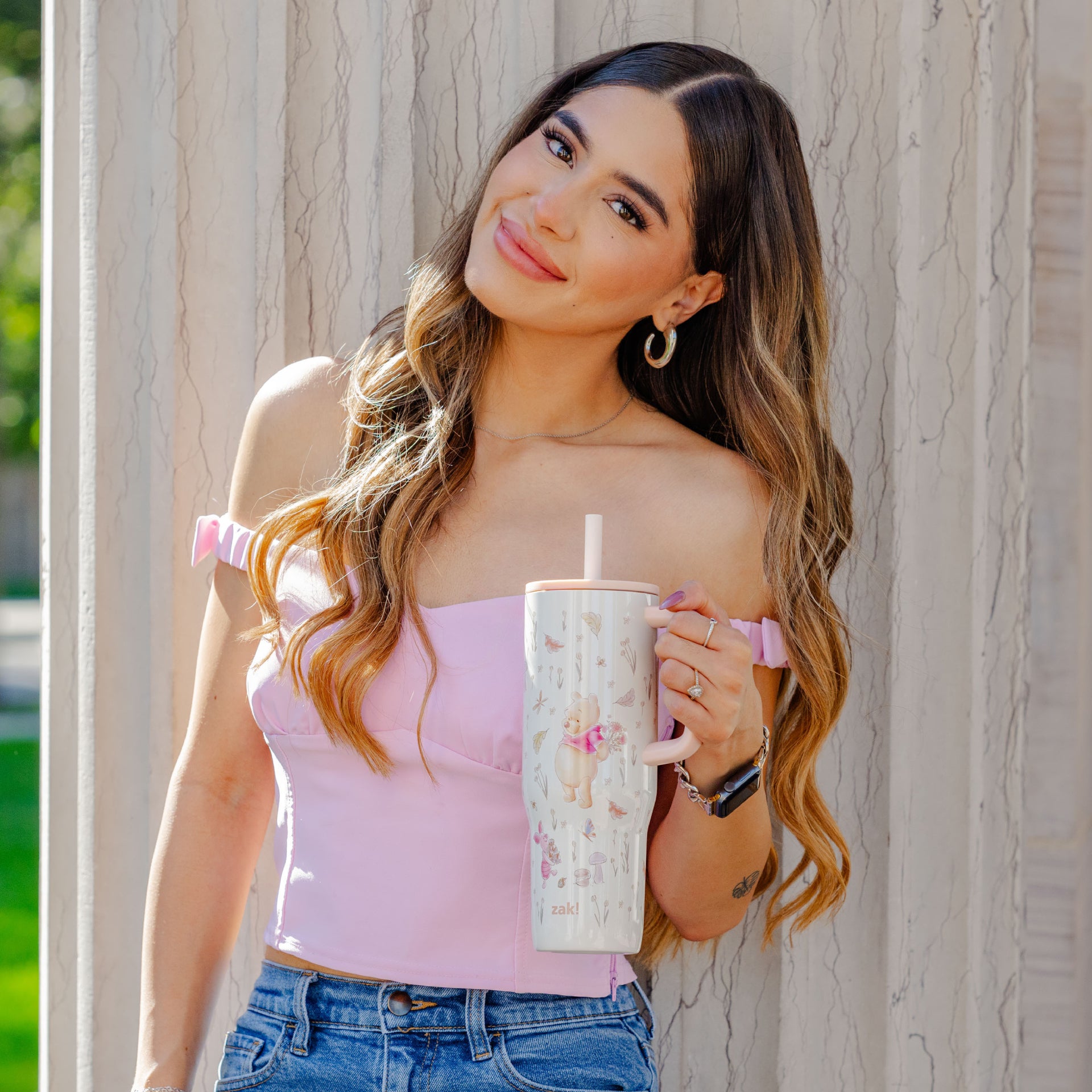 Woman holding a floral-patterned tumbler against a wooden background