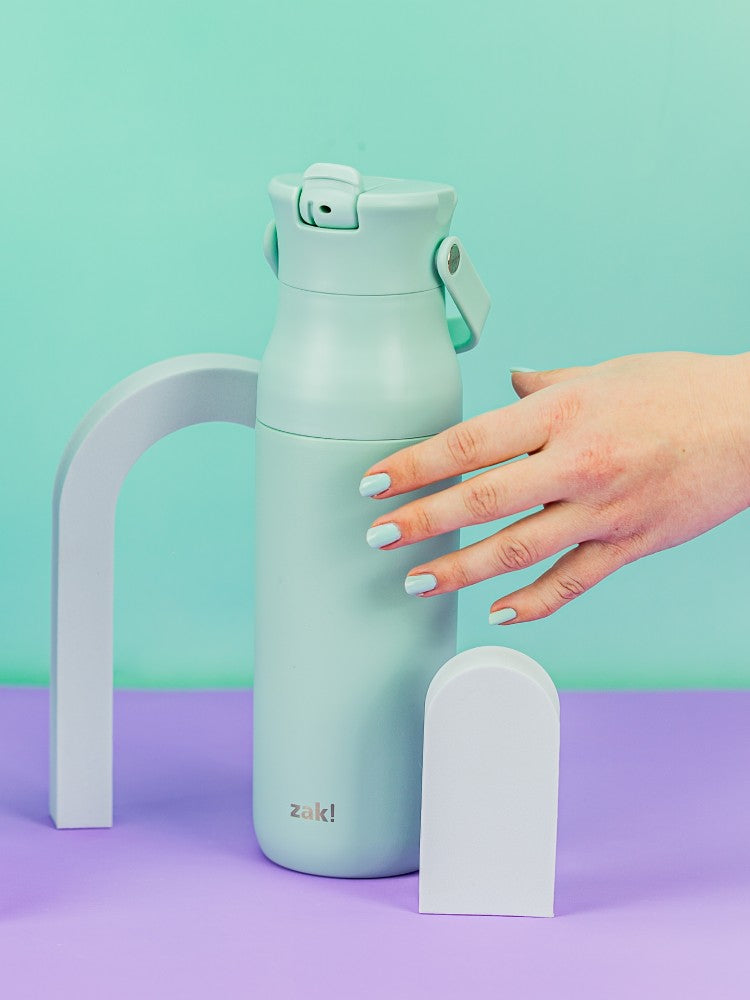 Mint green zak water bottle with a white base on a purple and teal background