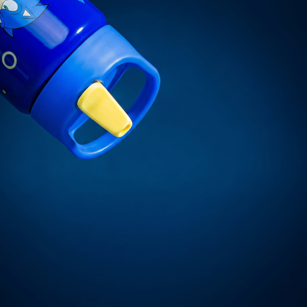 A close-up of a blue water bottle lid with a yellow flip spout, shown against a dark blue gradient background.