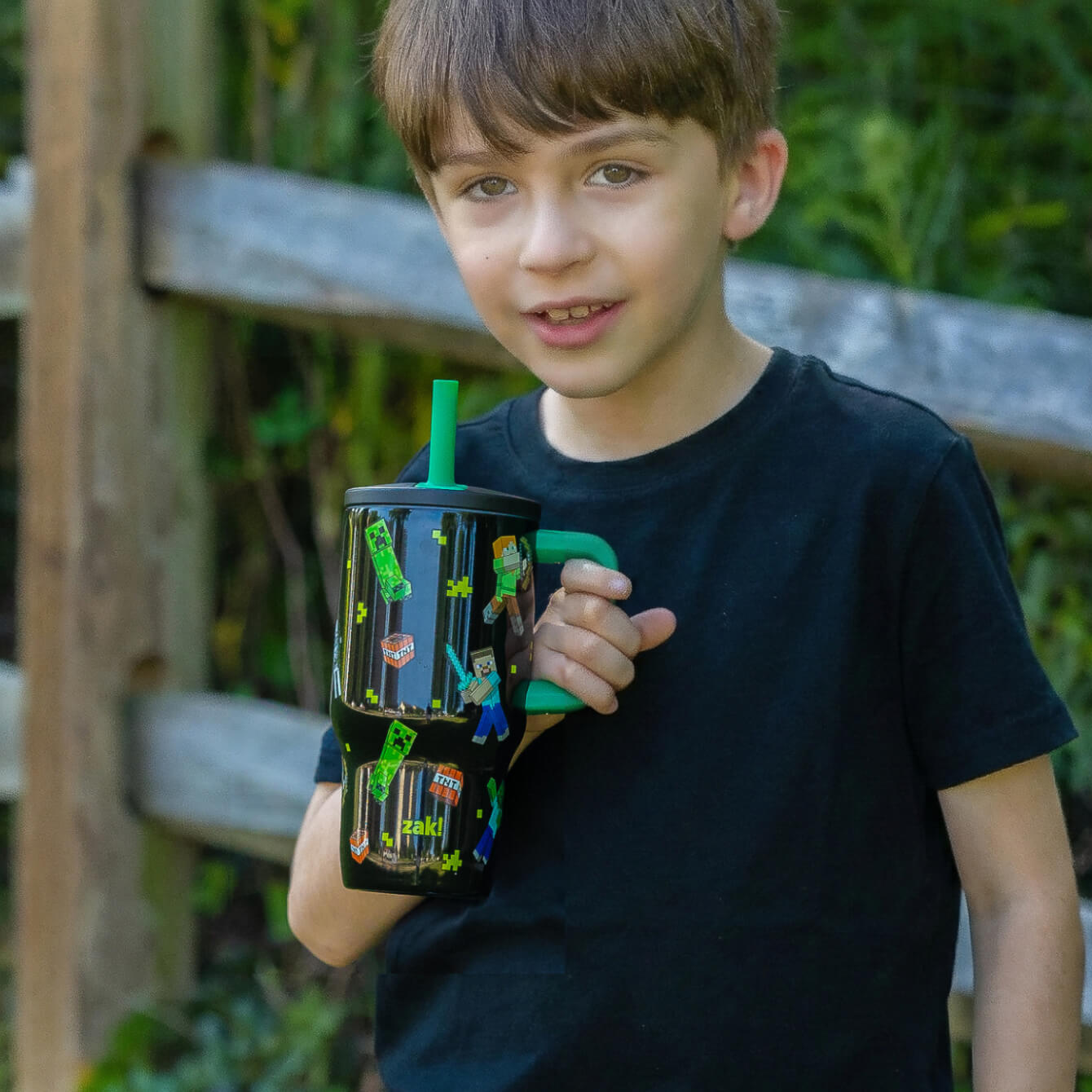 boy in black shirt holding a minecraft tumbler with green straw