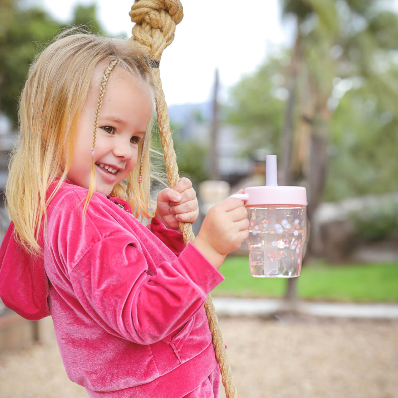 happy girl at the park holding a pink straw cup