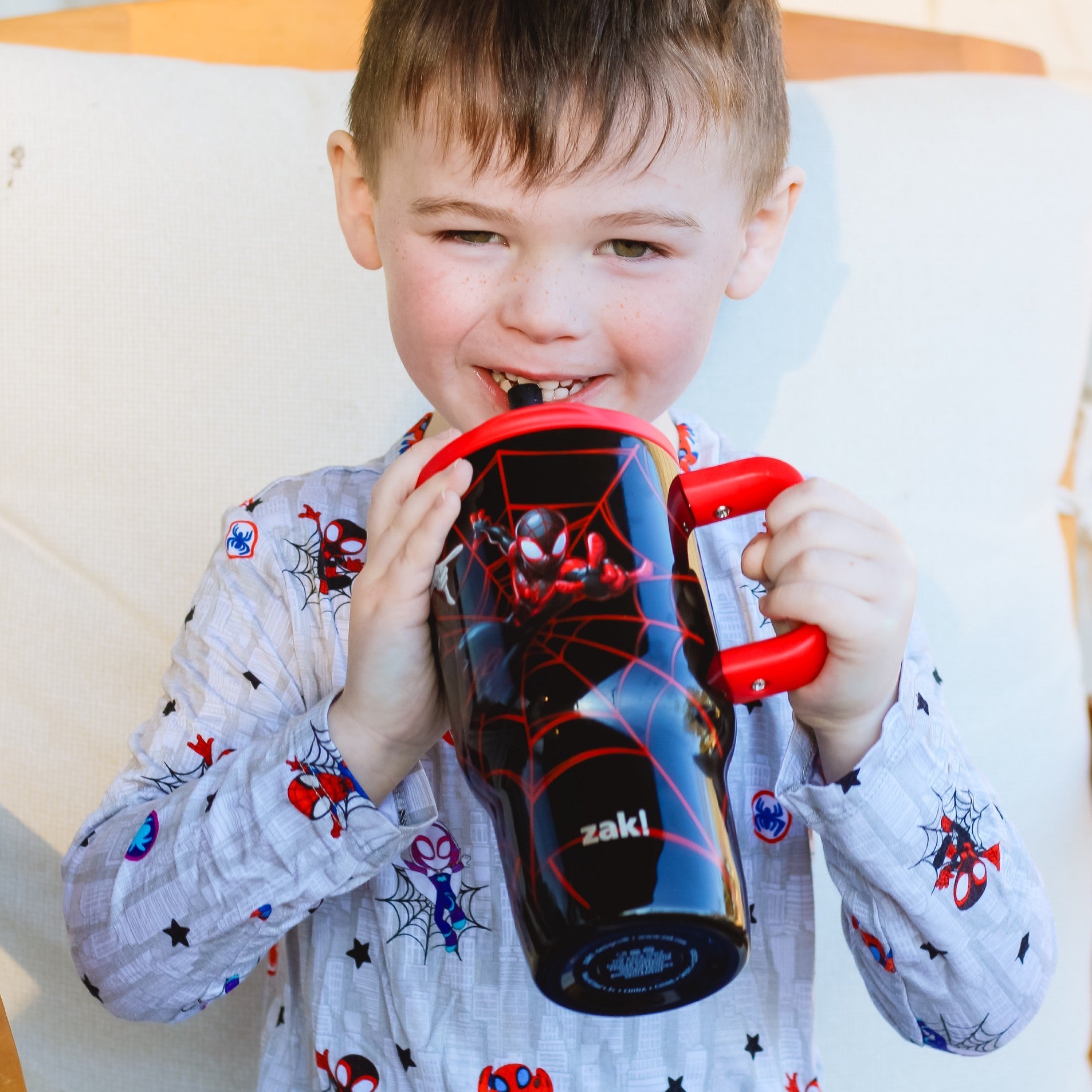 Boy sipping from Spiderman tumbler with red handle