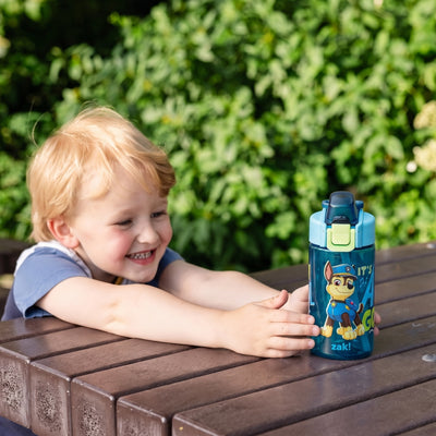 boy reaching for PAW Patrol water bottle sitting on table