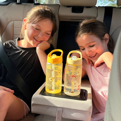 Kids in back seat of car holding two yellow water bottles