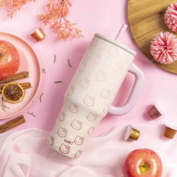 Hello Kitty-patterned mug on a pink background with apples and flowers