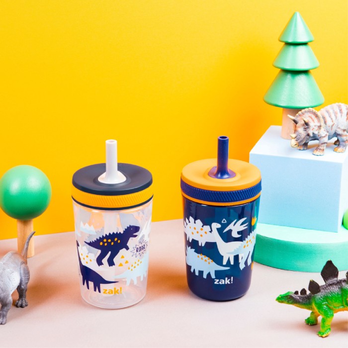 Two children's tumblers with dinosaur designs on a colorful background with toys.