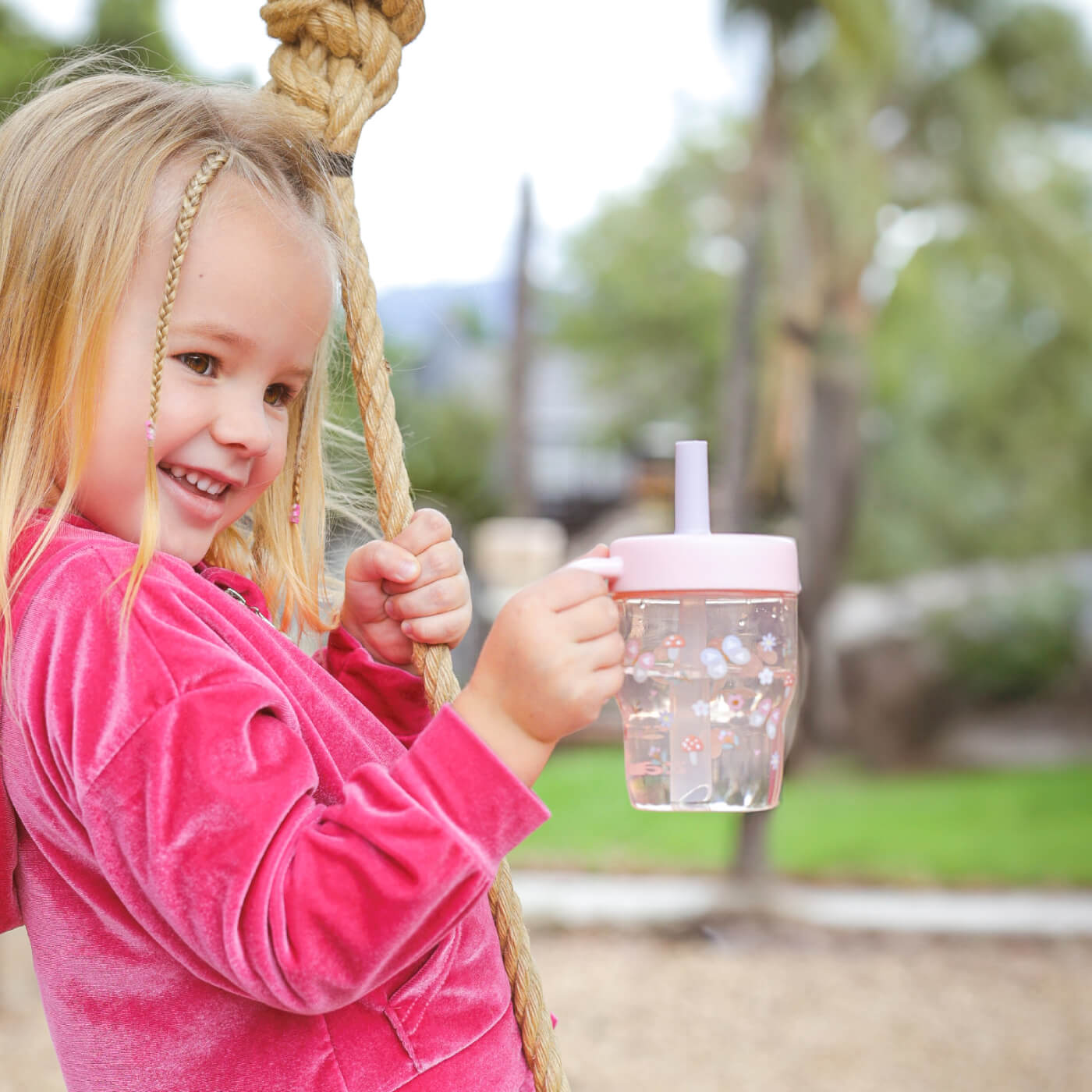 Toddler holding pink leakproof straw tumbler with flower artwork