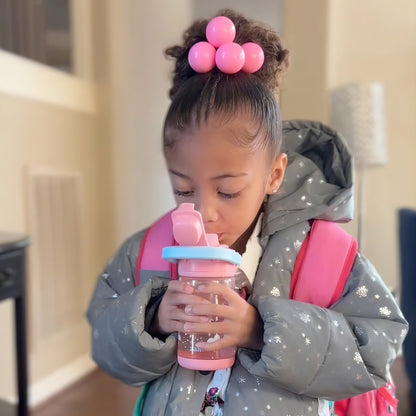 Child with pink backpack and hair accessories drinking from a pink zak water bottle.