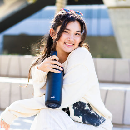 Young woman with a smile holding a black zak water bottle