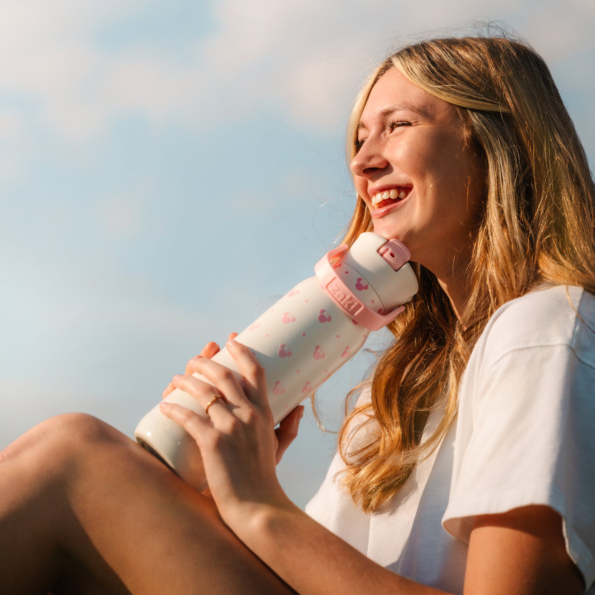 Girl holding white and pink water bottle outside on sunny day