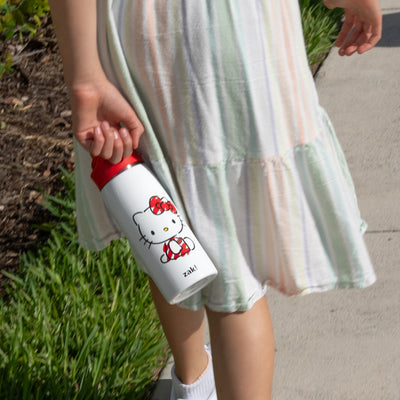 Girl holding a Hello Kitty water bottle with a striped dress.