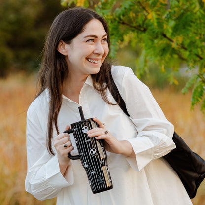 Woman in white top carrying zak! black and white travel tumbler